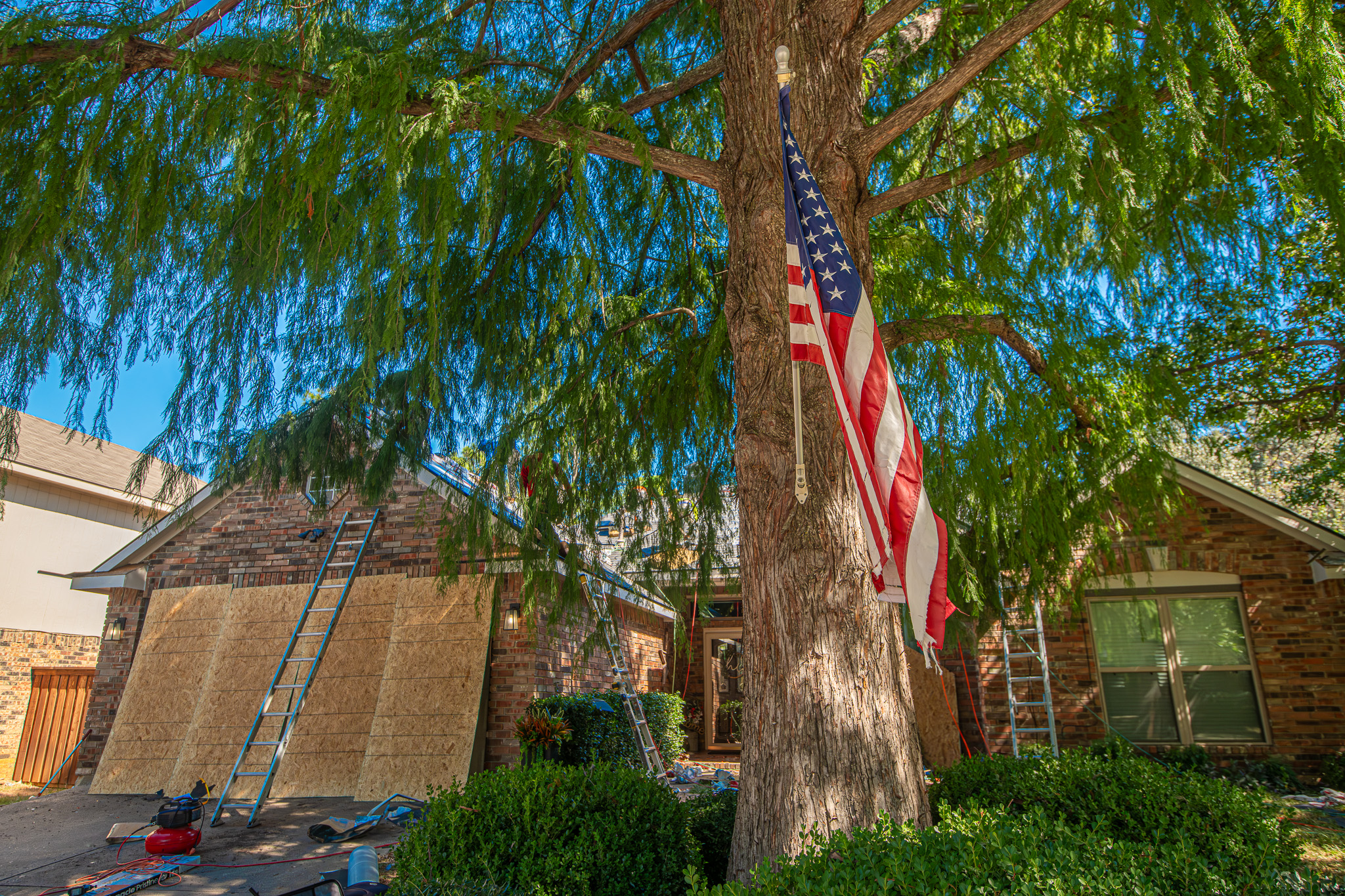 American flag on a tree in front of a North Texas home having its shingles replaced.